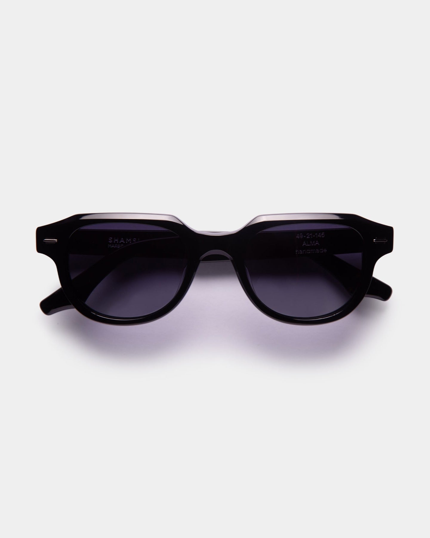 A pair of black ALMA sunglasses with a slightly rounded silhouette, displayed against a white background.