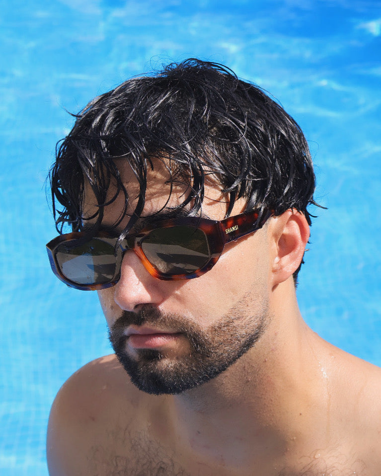 Man wearing sunglasses with a pool in the background