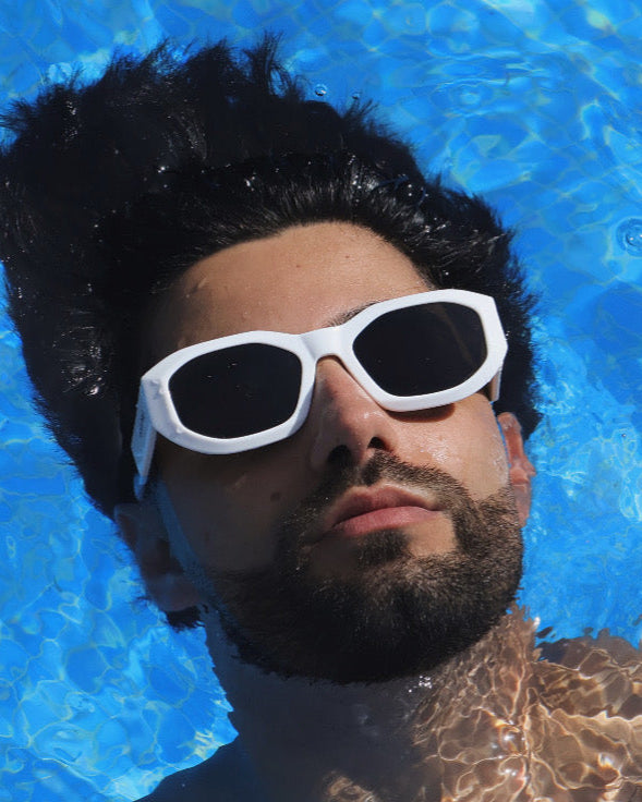 Man wearing white sunglasses in a pool with blue water