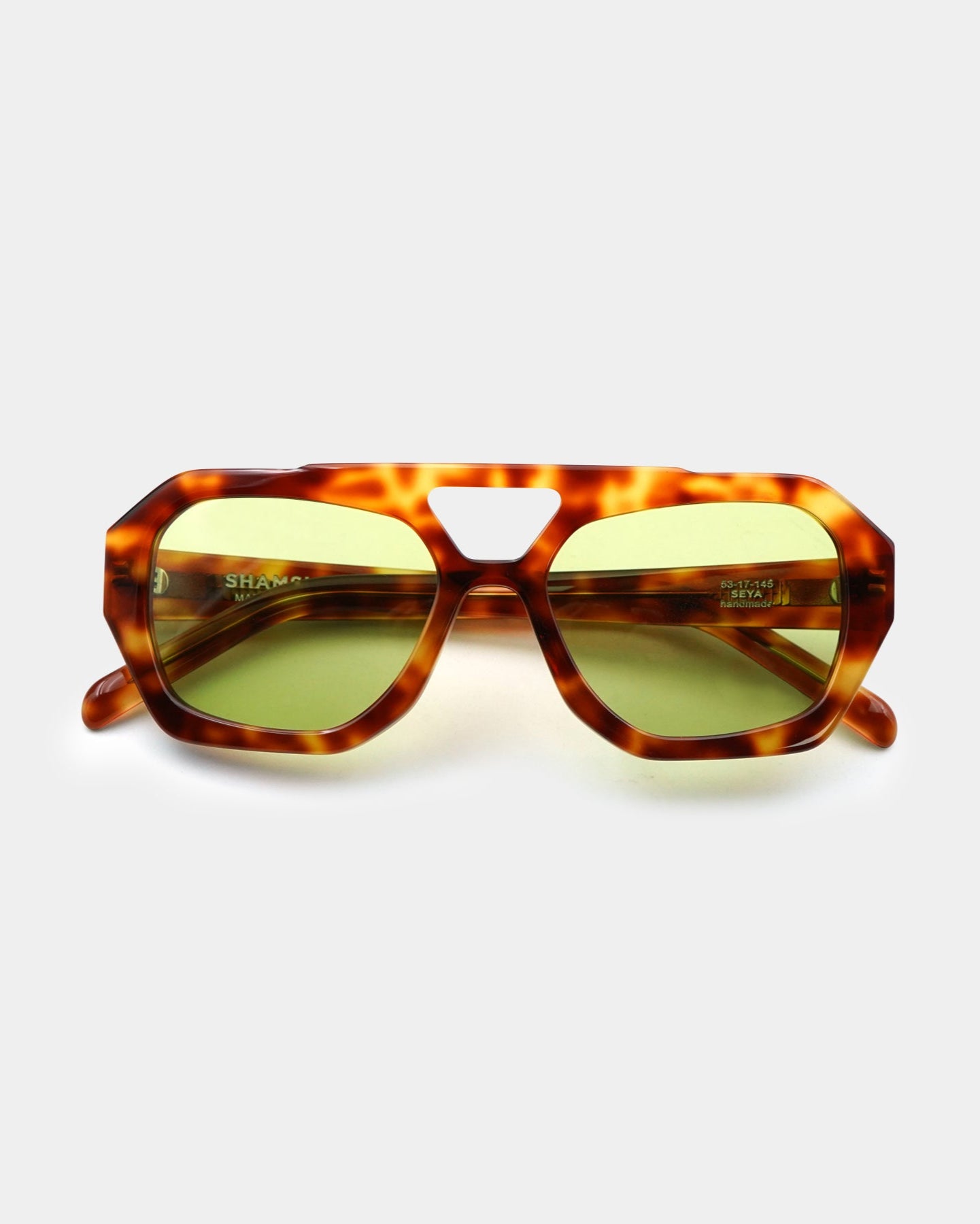 Tortoiseshell sunglasses with green lenses on a white background