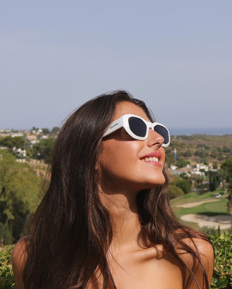 Woman wearing white sunglasses with a scenic background