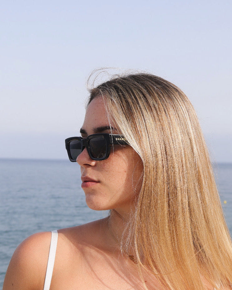 Woman wearing sunglasses with a blurred ocean background