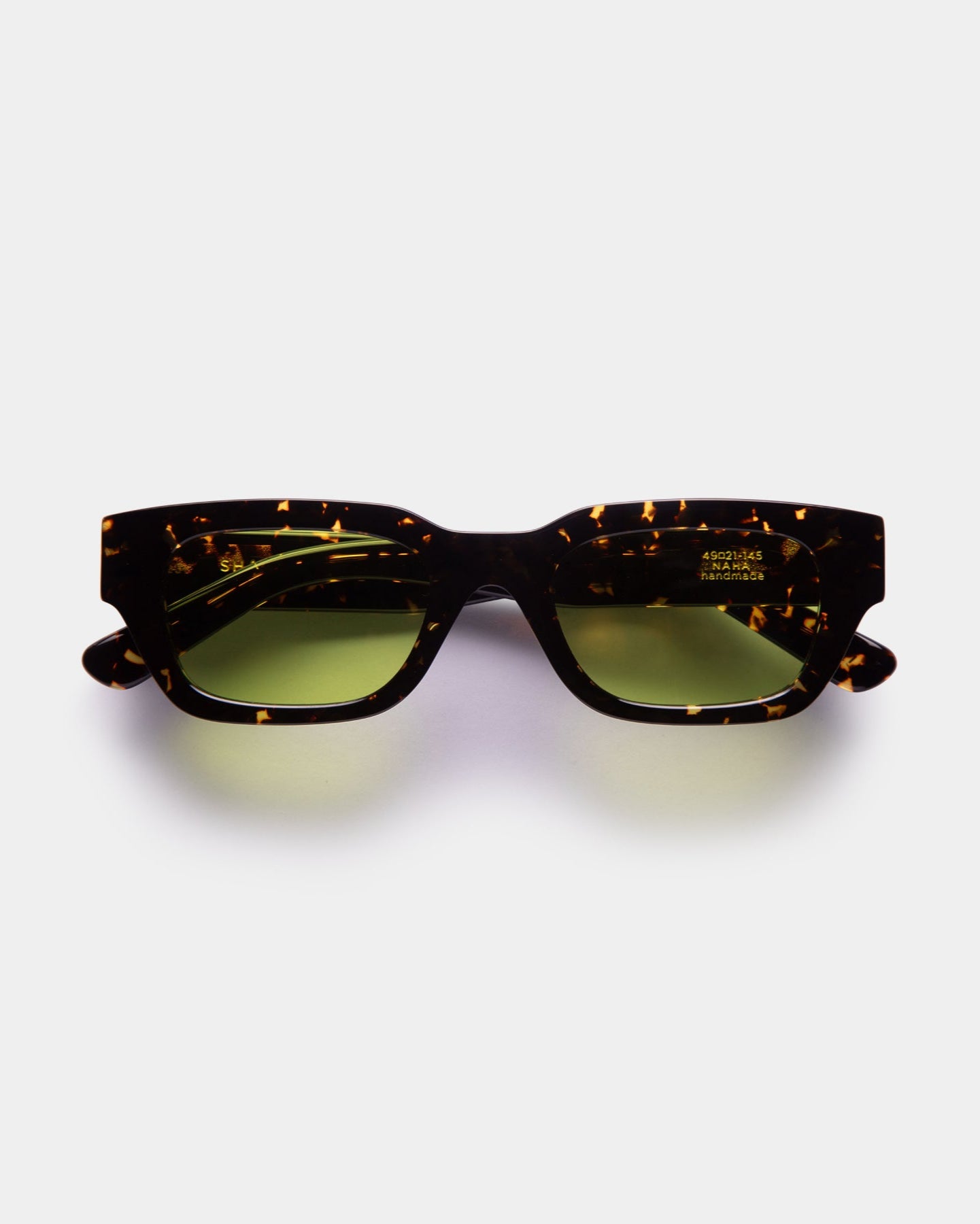 Sunglasses with tortoiseshell frame and green lenses on a white background