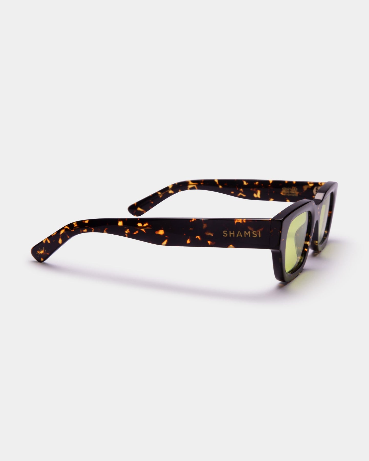 Sunglasses with tortoiseshell frame and green lenses on a white background