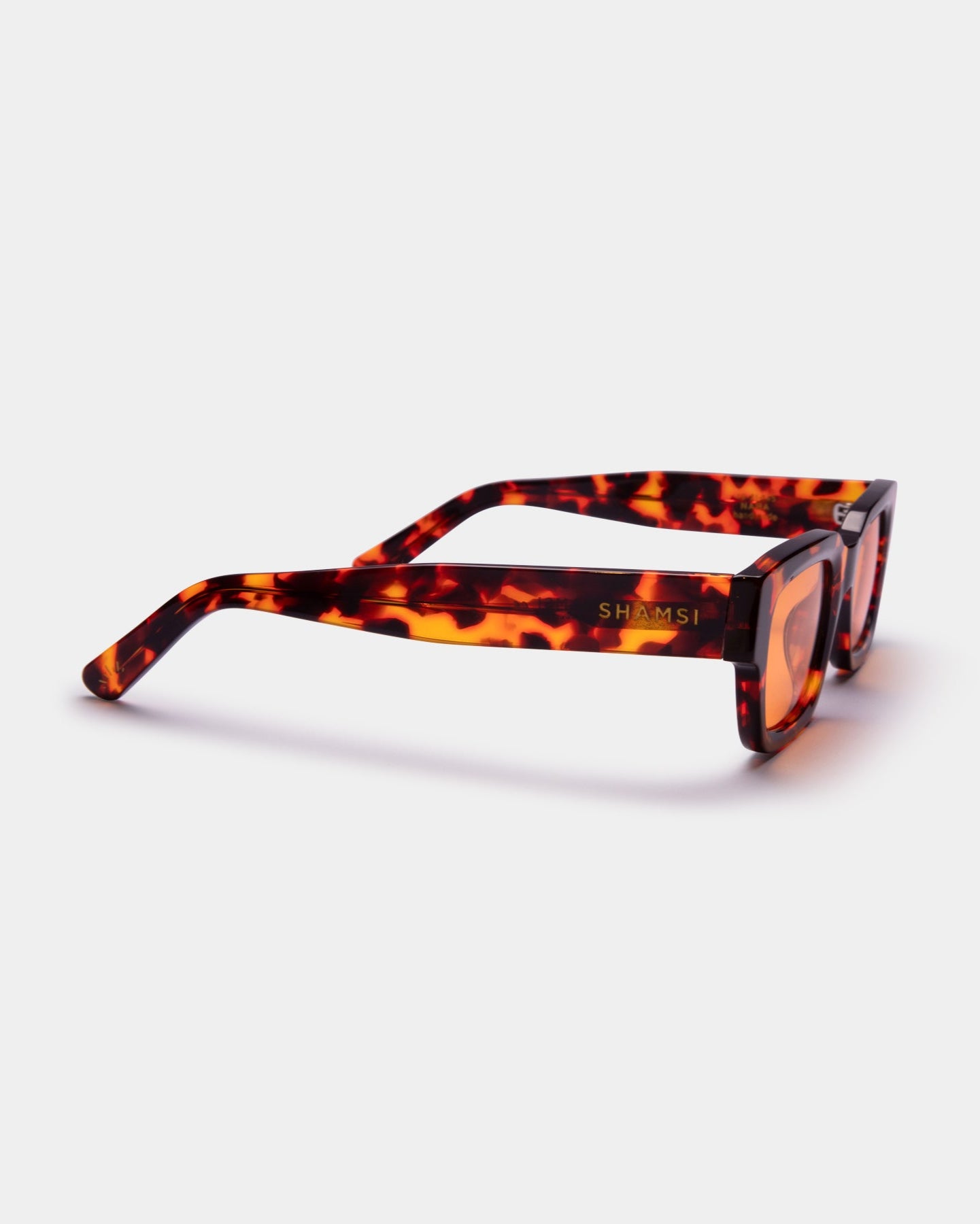 Sunglasses with tortoiseshell frame and orange lenses on a white background