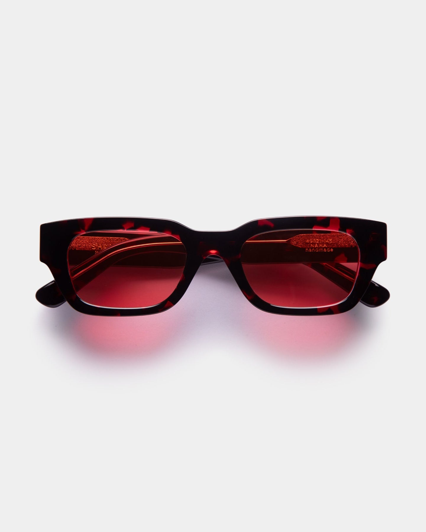 Sunglasses with red lenses on a light gray background