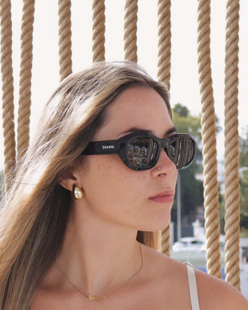 Woman wearing sunglasses with a rope fence background