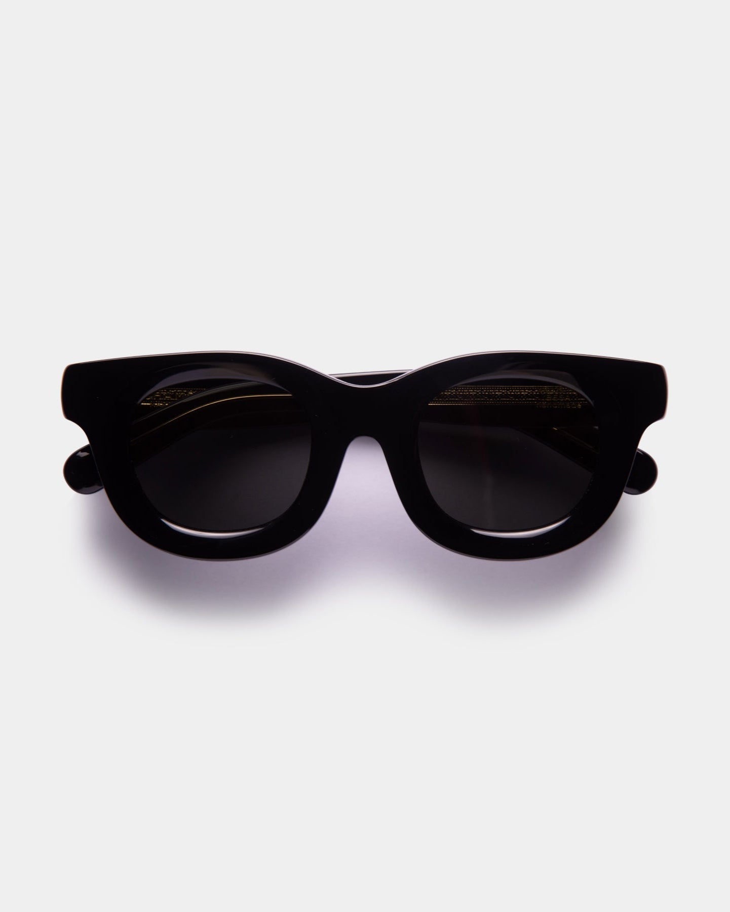 A pair of black rounded sunglasses with a box, protective case, and microfibre cloth for cleaning.