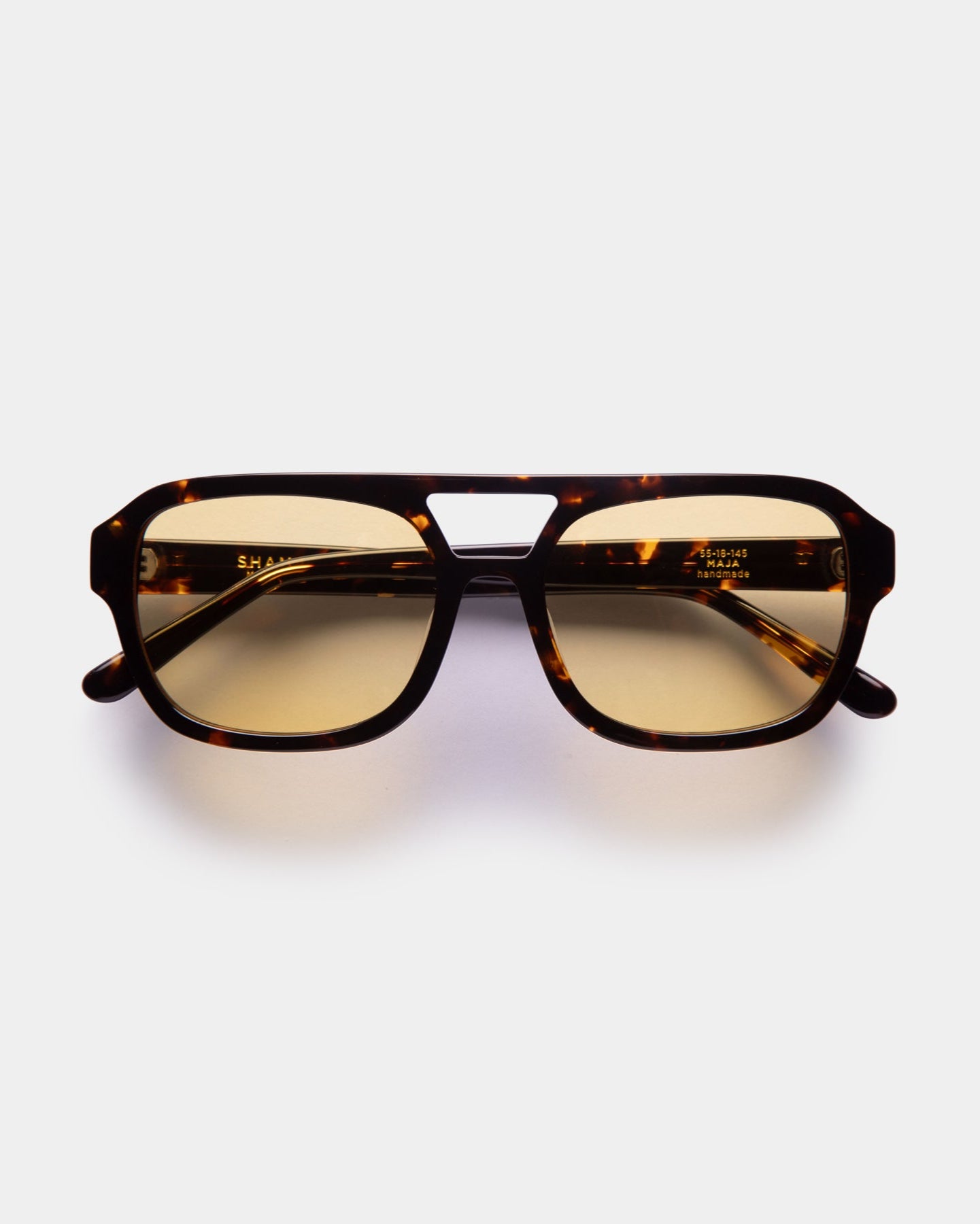 A pair of unisex pilot-style sunglasses with a '90s aesthetic, featuring a refined frame and high-quality lenses, displayed against a white background.