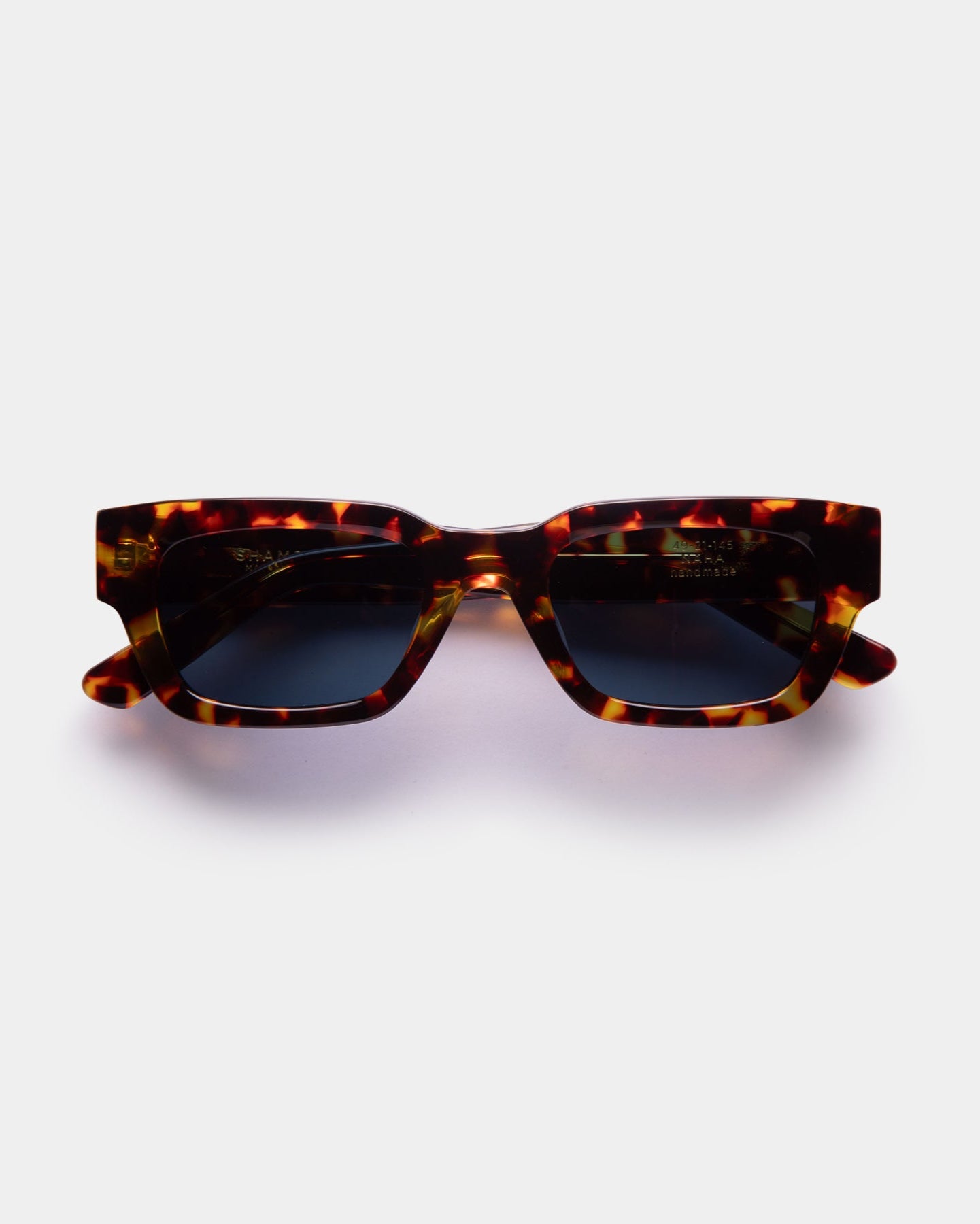 A pair of sunglasses with a patterned frame, black lenses, and a nose bridge.