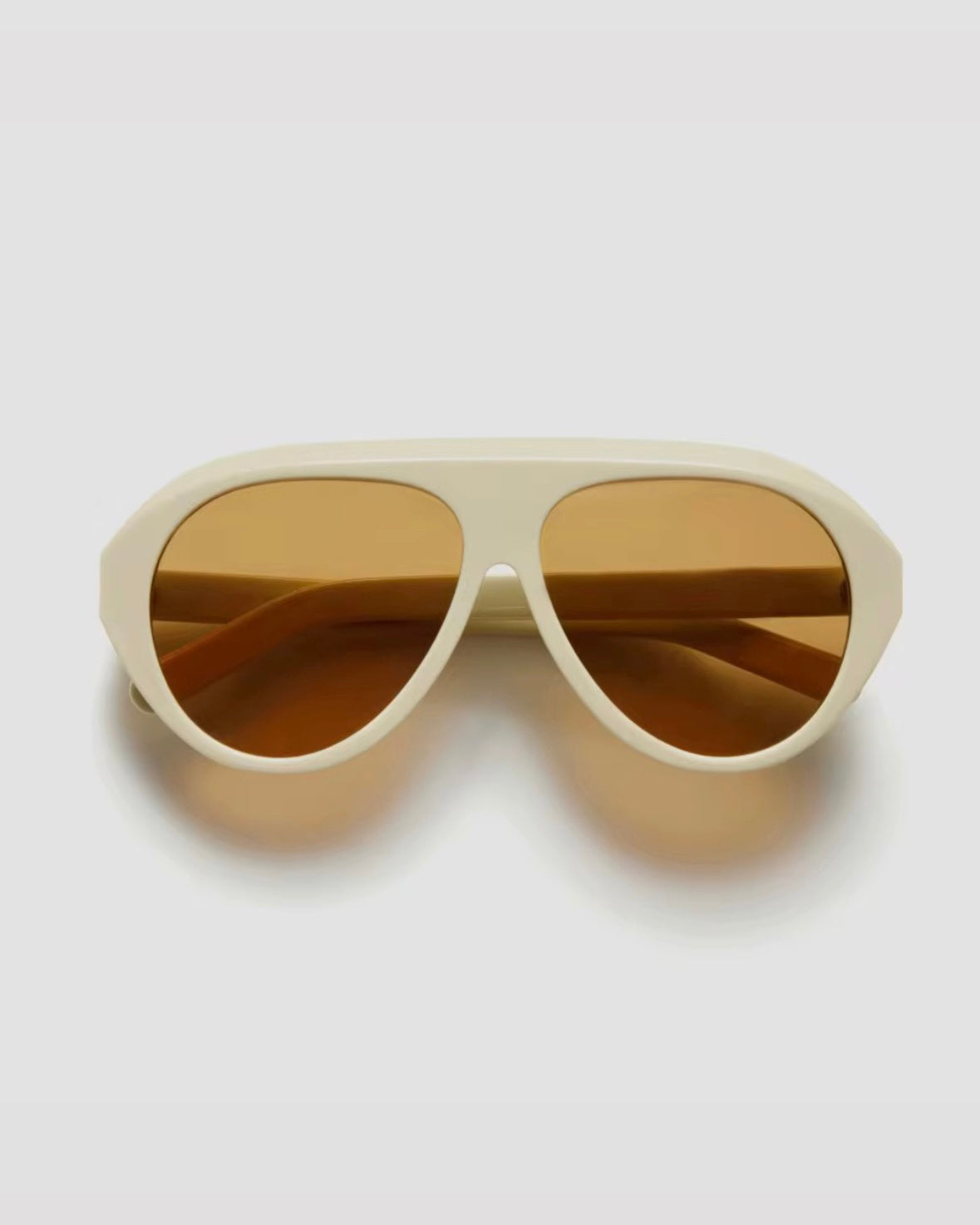 Beige sunglasses with brown lenses on a white background